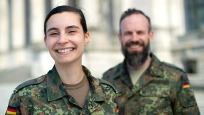 Eine Soldatin und ihr Kamerad lächelnd im Dienst