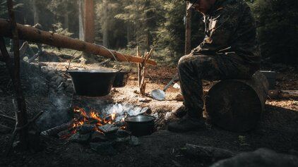Ein Soldat der Bundeswehr sitzt in einem Wald am Lagerfeuer