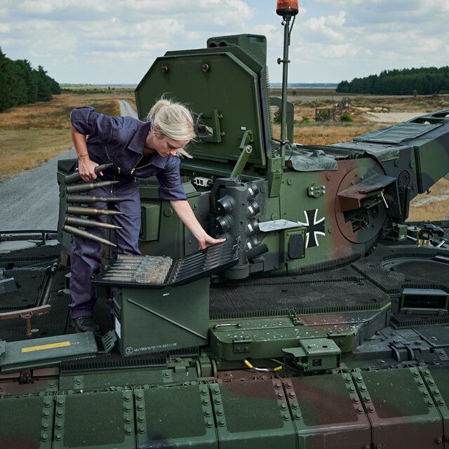 Eine Technikerin erledigt technische Arbeiten auf einem Panzer