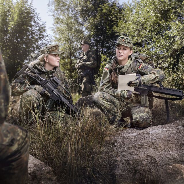 Soldat_innen besprechen im Rahmen einer Übung die Lage im Wald. 