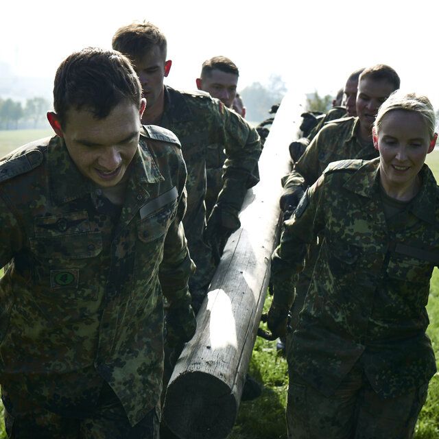 Soldat_innen der Bundeswehr tragen einen Stamm im Rahmen einer Übung. 