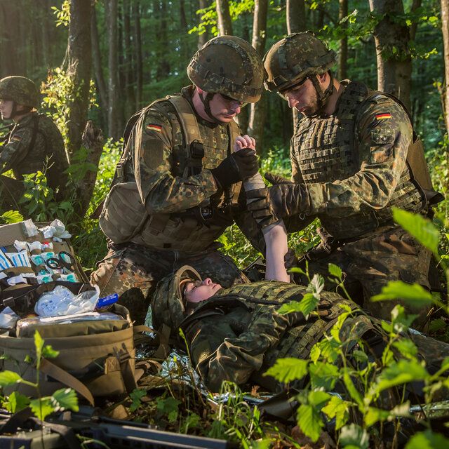 Zwei Soldaten im Dschungel leisten einem verwundeten Kameraden erste Hilfe. 