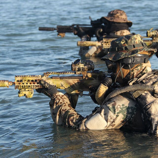 3 Soldaten der Spezialkräfte bewegen sich langsam durchs Wasser. Zu sehen sind nur ihre Oberkörper und ihre Waffen
